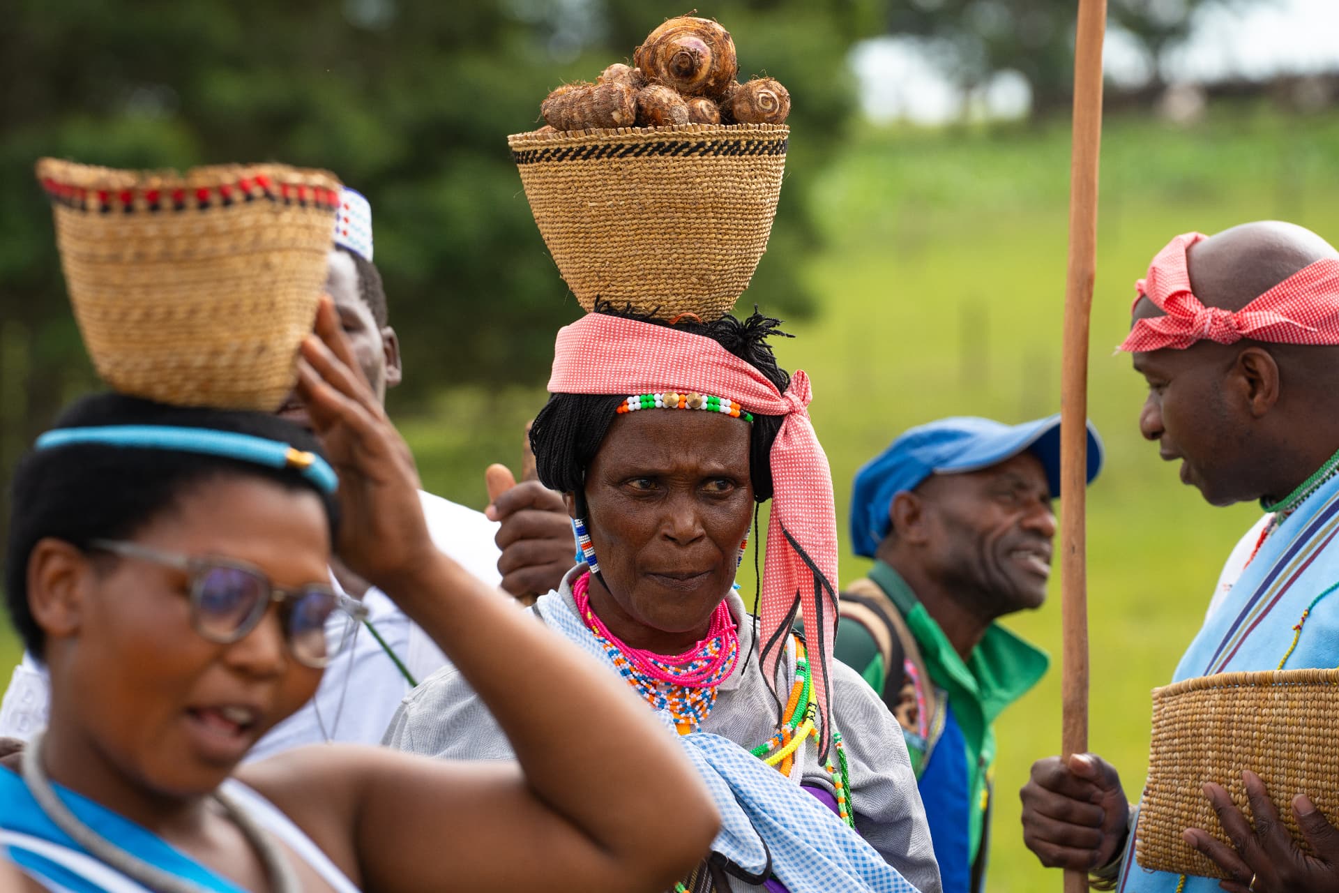 Community members carrying woven baskets of harvested produce